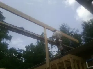 Carpenter setting a ridge beam over a new addition frame — Ice Dam Removal by Roofing Brothers in Solomons
