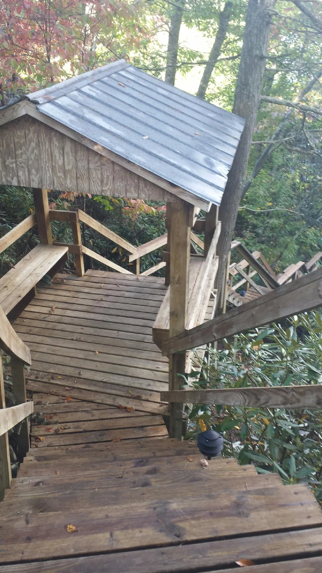 Metal roofed shelter over wooden steps on a wooded walkway — Skylight Repair & Installation work by our crew in Solomons